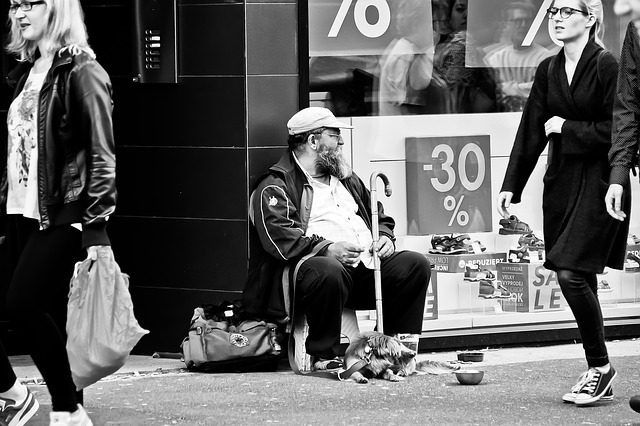 A black and white photo of a man sitting outside the store
