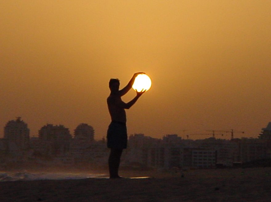 A silhouette of a man holding the sun in his hands